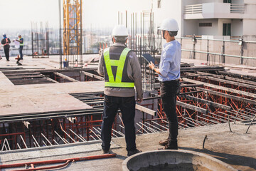 Two engineer in hardhat and orange jacket posing on building site. civil engineer or architect with...