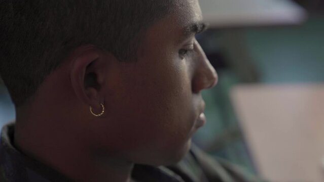 Very close up handheld frame of the right side profile of a Native American boy's face in class.
