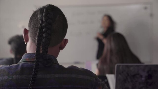Young Indigenous student taking notes from the back of the classroom