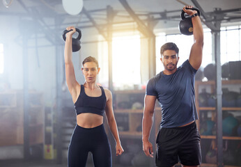 Fitness couple doing a kettlebell workout, exercise or training in a gym. Fit sports people, woman...