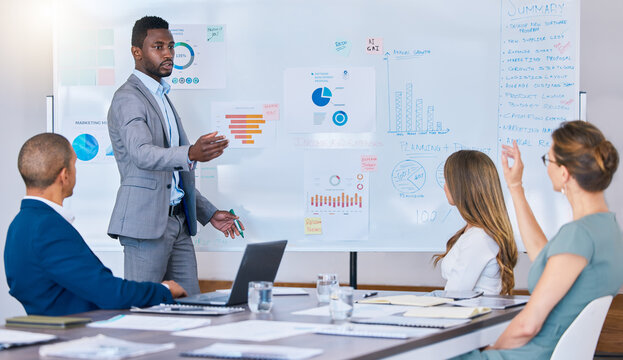 Presentation, strategy discussion or meeting of business man briefing his colleagues in a boardroom. African American leader accountant answers questions in an office while discussing finance