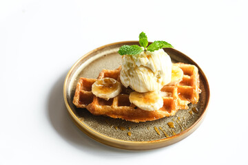 Caramelized Croissant Waffle or Croffle with banana slice and ice cream topping, served on brown plate
