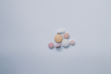 Pills of different colors and sizes on a white background.