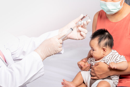 Close-up images, Doctor's hand which prepares to vaccinate against virus, with blur background of mother is holding baby newborn is 3 montsh old, to baby newborn health care and vaccine concept.