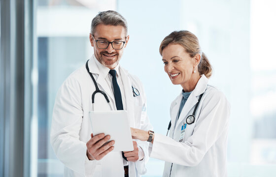 Medical, doctors and healthcare professionals working together on a digital tablet in a hospital. Portrait of a mature female and male doctor smiling and discussing diagnosis in a clinic. - Powered by Adobe