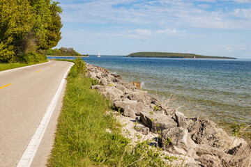 Two lane road on Mackinac Island with Lake Huron and Round Island in background, Michigan