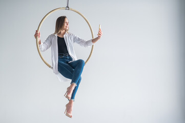 Caucasian woman gymnast on an aerial hoop takes a selfie on a smartphone.  © Михаил Решетников