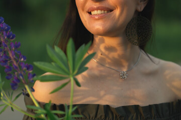 An attractive woman in a field with a summer bouquet of wildflowers Lupinus. Front view.