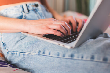 A girl works from home, female hands on a laptop keyboard close-up