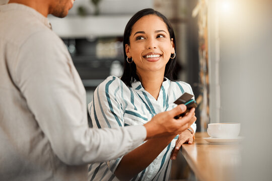 Customer paying using contactless credit card, standing by cafe or restaurant bar counter. Smiling woman make cashless payment for coffee bill with wireless NFC tag reader technology POS machine.