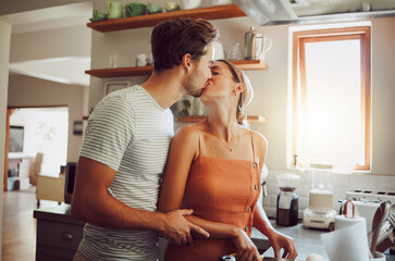 Romantic couple kissing, cooking and showing affection in love while bonding together in a kitchen...