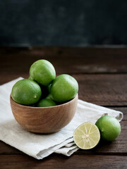 Fresh lime citrus fruits in wooden bowl on the table. Selective focus image and blurred background.
