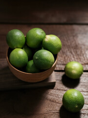 Fresh lime citrus fruits in wooden bowl on the table. Selective focus image and blurred background.
