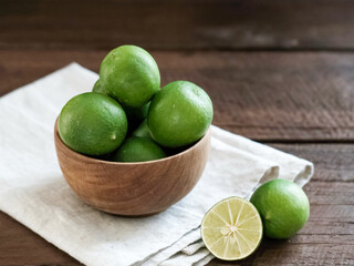 Fresh lime citrus fruits in wooden bowl on the table. Selective focus image and blurred background.
