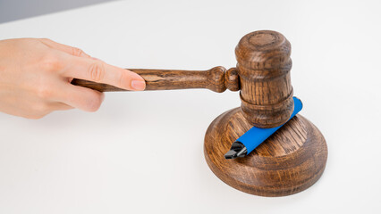 Judge hammering disposable vape with referee's gavel on white table. 