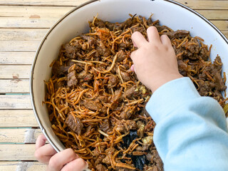 Hands holding a bowl of Sambal Goreng Daging (Gore Gore) cuisine from Indonesia, made from slices...