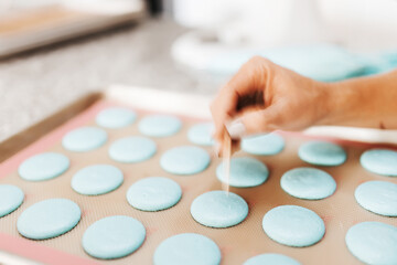 Obraz na płótnie Canvas The process of making macaroons. Cookie baking. A woman prepares macaroons for baking. Blue macaroons