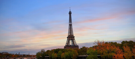 Fototapeta na wymiar Eiffel Tower, iconic Paris landmark as autumn trees park across the River Seine with tourist boat in sunset sky scene at Paris ,France