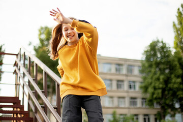 A teenage girl has fun and slides down the railing at the stadium