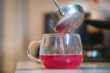 Hot kissel in the transparent cup close up on the kitchen table.