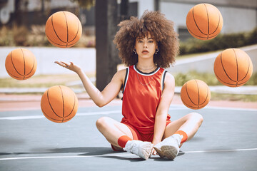 Naklejka premium Female basketball player sitting with balls in the air on a court, learning fitness training and doing sport exercise and workout outside. Portrait of a black woman playing game and looking confident