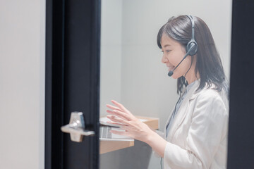 シェアオフィスの個室ブースでリモート会議をする女性