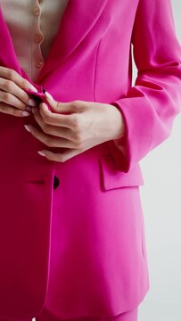 Woman unbuttoning business suit jacket, no face, vertical