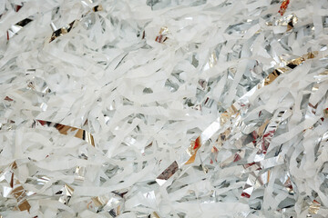 Textured background of shredded paper, top view of many strips of white paper. A stack of cut paper, for example, confetti for a party or a filler for boxes for transporting fragile items