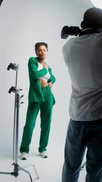 Photographer and model work in studio, vertical video