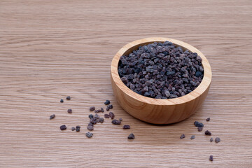 Fototapeta na wymiar Himalayan black salt in bowl on wooden texture background