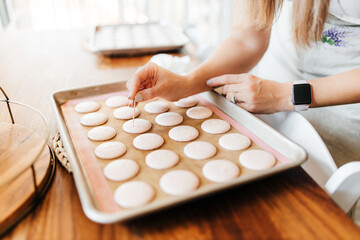 The process of making macaroons. Cookie baking. A woman prepares macaroons for baking. Hands close up