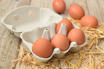 Brown chicken eggs in six package carton box closed up on yellow straw