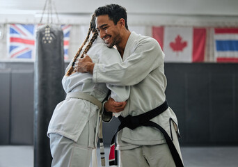 . Karate trainer giving hug to female student for motivation, coach embracing for support and celebration after winning competition. Teammates and friends training and learning martial arts at a gym. © Delcio F/peopleimages.com
