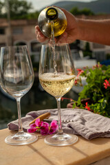 Pouring in glasses of cold white wine in yacht harbour of Port Grimaud, summer vacation on French Riviera, France