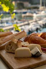 Sunny morning in Provence, breakfast with fresh baked croissants, baquett bread, crottin goat cheese and view on fisherman's boats in harbour of Cassis, Provence, France