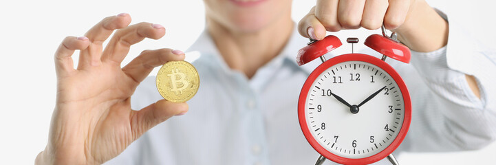 Woman is holding golden bitcoin and alarm clock