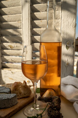 Cold rose wine in glass and bottle served with goat cheeses on outdoor terrace with view on old...
