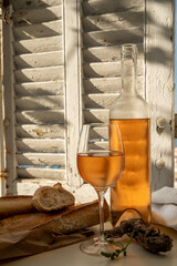 Cold rose wine in glass and bottle served on outdoor terrace in sunlights with view on old...