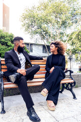 Coworkers chatting on park bench outdoors enjoying themselves happy, business partners chatting on park bench outdoors on sunny day