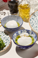 Aesthetic composition with burrata cheese and mozzarella in olive oil. Fresh burrata and mozzarella cheese in ceramic bowl. Italian cuisine. Dairy cheese: mozzarella buffalo and creamy burrata.