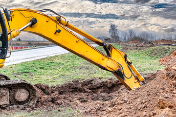 Close up of excavator bucket at construction site. The excavator is digging a trench for underground utilities. Construction equipment for earthworks.
