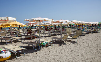 Italian beach view with umbrellas and sunbeds. Summer day on the beach. Riviera Romagnola, Italy