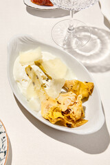 Italian antipasti - grilled artichoke with cheese and mayo sauce. Vegetable appetizer from artichoke and sauce on white table. Italian lunch with Roasted artichoke on sunny day. Trattoria menu.