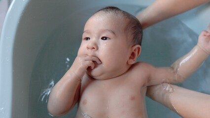 Top view of Cute baby having bath. Mother holds and bathes baby