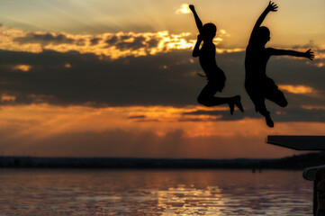 Zwei Kinder springen an einem schönen Sommerabend in einen See