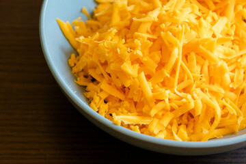 grated cheddar cheese on a plate on wood table
