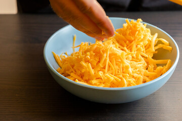 grated cheddar cheese on a plate on wood table
