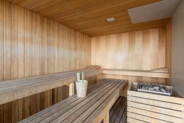 Classic wooden interior of Finnish sauna with benches and loungers accessories for hot procedures.