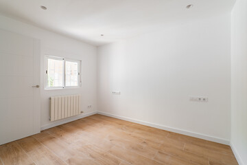 Empty room after renovation with window, white walls and wooden floor in new apartment