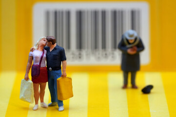 Couple carrying shopping bags, kissing next to a beggar.